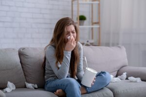 Brokenhearted young woman with bucket of ice cream crying while watching drama on TV at home